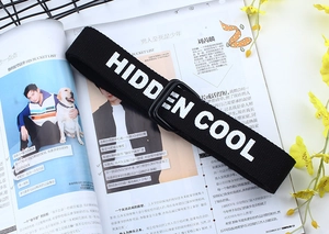 Gros plan sur la ceinture en toile noire avec broderie HIDDEN COOL et boucle en D