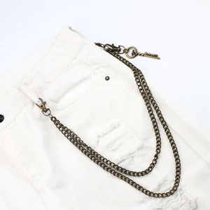 Detail of vintage bronze double-layered metal trousers chain with engraved pendants on jeans