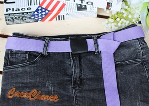 Detail of purple woven canvas belt with black square buckle on grey denim clothing