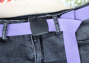 Detailed close-up of a purple woven nylon belt with a matte black plastic buckle