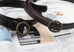 Détail de fines ceintures en cuir avec boucles rondes dorées torsadées sur un magazine