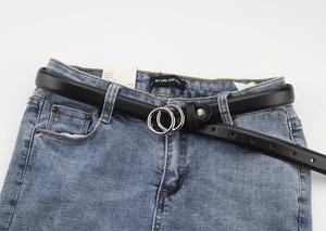Close-up of black leather slim belt with silver double O-ring buckle on denim jeans
