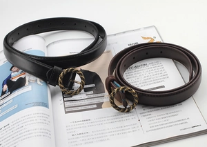 Détail d'une boucle ronde tressée sur de fines ceintures en cuir noir et marron