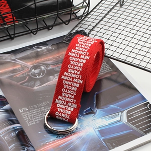Detail of red woven canvas belt with white city names and double D-ring metal buckle