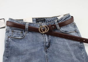 Detail of vintage brown PU leather belt with gold double ring buckle on blue jeans