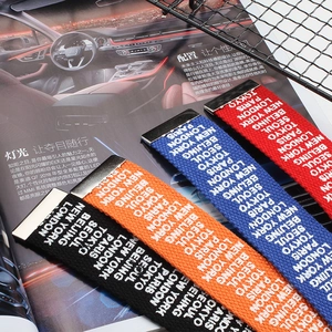 Detail of woven fabric belts featuring urban city names and metal buckles in four colors
