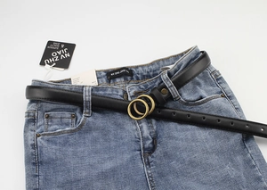 Detail of a vintage black leather belt with double gold rings on denim jeans