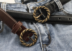 Gros plan de ceintures fines en cuir noir et marron avec boucles dorées torsadées