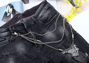 Detail of triple-layer metallic pant chains and distressed denim texture with industrial style