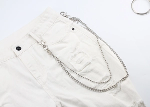Détail d'une chaîne de pantalon double couche en métal argenté sur un jean blanc