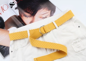 Close-up of yellow polka dot nylon belt with double D-ring buckle on denim shorts
