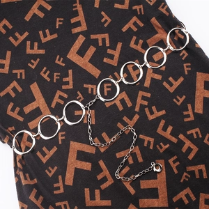 Detail of silver metal link waist chain with round rings and extension charm on fabric