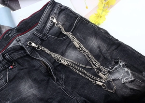 Close-up of triple-layered silver metal hip hop pant chains with spring charms on ripped jeans