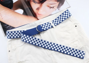 Détail de la ceinture en toile à carreaux bleus et blancs avec boucle double D