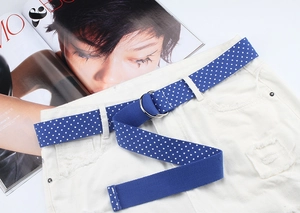 Close-up of blue polka dot nylon canvas belt with double D-ring metal buckle on jeans