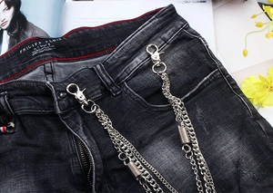 Detailed close-up of double layer silver metal chain on dark washed denim jeans