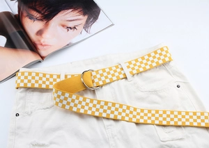 Détail de la ceinture en toile à damier jaune avec boucles doubles D sur un jean