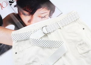 Close-up of white canvas belt with black polka dots and silver double D-ring buckle
