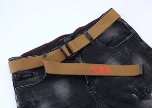 Détail de la ceinture en toile de nylon beige avec texte japonais rouge et boucle double D