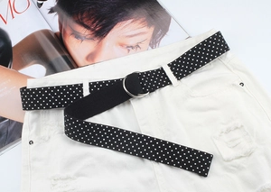 Close-up of black and white polka dot canvas belt with double D-ring on white denim