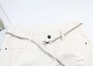 Gros plan d'une chaîne de pantalon en métal argenté punk hip-hop sur un short blanc