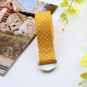 Detail view of yellow canvas belt with white polka dots and silver metal D-ring buckle
