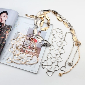 Detail view of heart-shaped metal chain belts and leaf pattern accessories in gold and silver