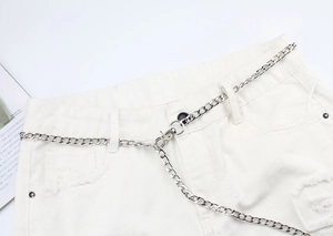 Détail d'une chaîne de pantalon en métal argenté avec grands anneaux sur un short
