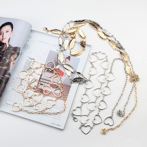 Detailed shot of leaf and heart metal waist chains with rose charms and lobster clasps