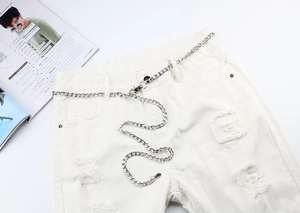 Détail de la chaîne de pantalon en métal argenté avec fermoir sur un jean blanc