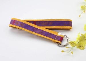 Macro detail of yellow canvas belt with purple silk ribbon and double metal D-ring buckle