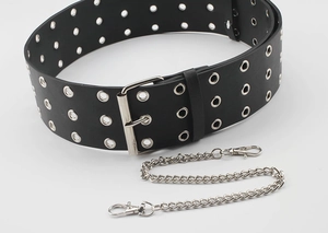 Detail of a punk style wide black PU leather belt with triple eyelets and silver metal chain