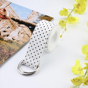 Close-up of white canvas belt with black polka dots and silver double D-ring buckle
