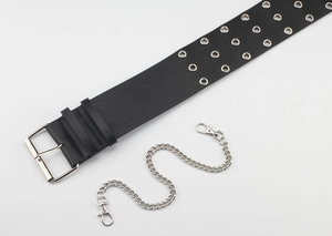 Detail of black wide faux leather belt with triple-row silver eyelets and chain accessory