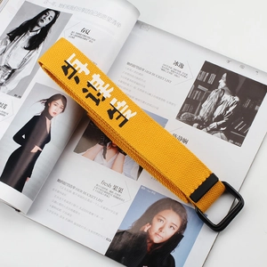 Detail of yellow canvas belt with double D-ring buckle and Optimism calligraphy