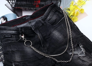 Detail of a double-layered metal hip-hop chain on distressed black denim jeans