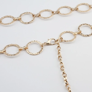 Close-up of golden hammered metal circle rings and lobster clasp on waist belt