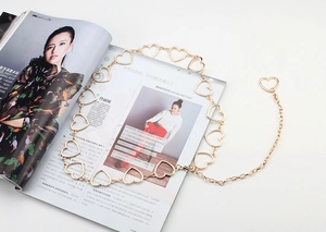 Detail of a gold heart-shaped metal link belt featuring hollow design and adjustment chain