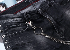 Detail of washed black jeans featuring double metal chains and branded logo tag