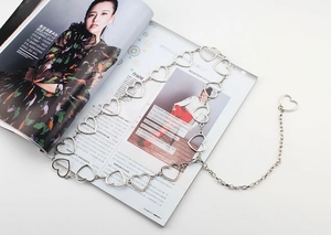 Detail view of a silver heart-shaped waist chain on a magazine with polished link texture