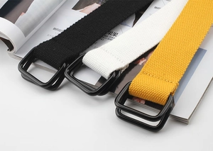 Close-up of black, white, and yellow canvas belts with matte black double D-ring buckles