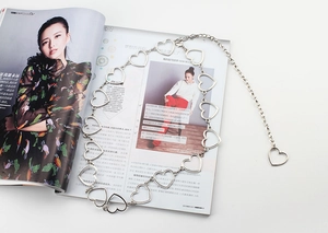 Close-up of a silver hollow heart-shaped metal waist chain on a fashion magazine
