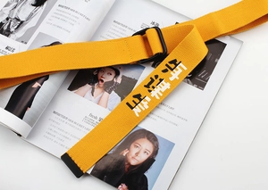 Detail of yellow canvas belt featuring black artistic text and durable metal buckle
