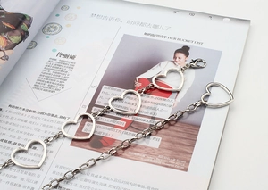 Detail of silver metal waist chain featuring hollow heart charms and lobster clasp