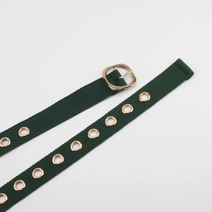 Détail d'une ceinture en toile vert foncé avec œillets dorés et boucle ardillon ronde