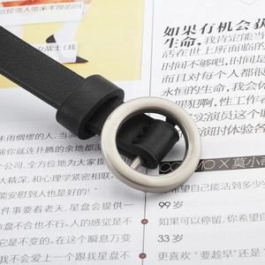 Close-up of a silver round buckle on a black slim leather belt with litchi texture