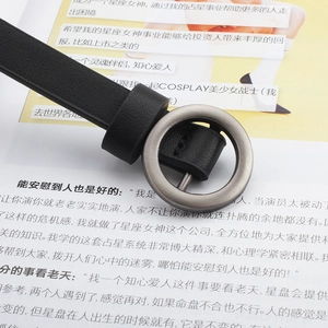 Detailed close-up of a slim black leather belt with a round silver-toned metal buckle