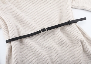 Close-up of a slim black leather belt with silver circular buckle on a knit dress