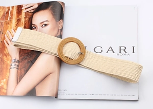 Detail view of a beige woven elastic belt with a round wood-style buckle on a magazine