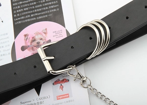 Detail eines Punk-Ledergürtels in Schwarz mit Silberringen und hängender Kette